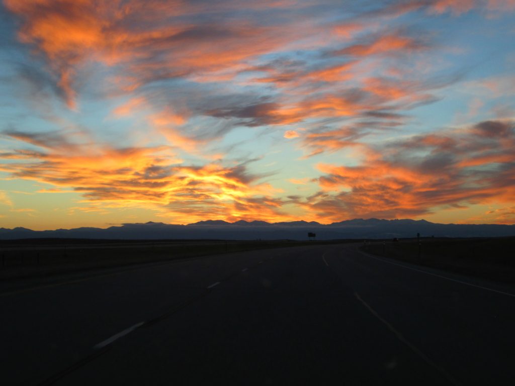 Clouds in the sky painted orange, pink, and red by the sunset over the Bighorn Mountains.